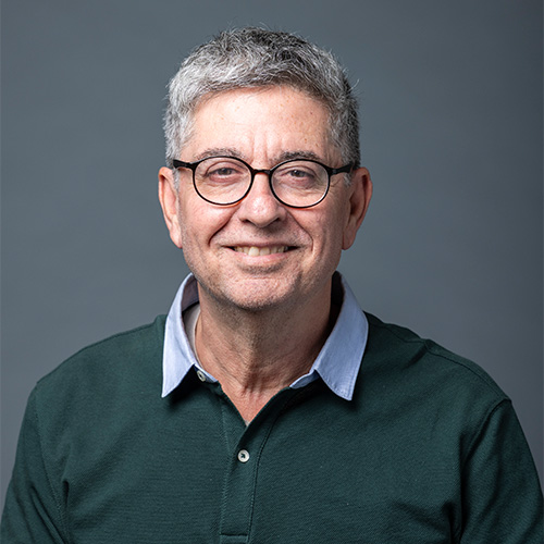 A headshot of Wassim Masri wearing a green sweater and glasses