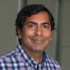 A headshot of CS professor Sanjeev Setia smiling and wearing a blue, plaid, collared shirt.